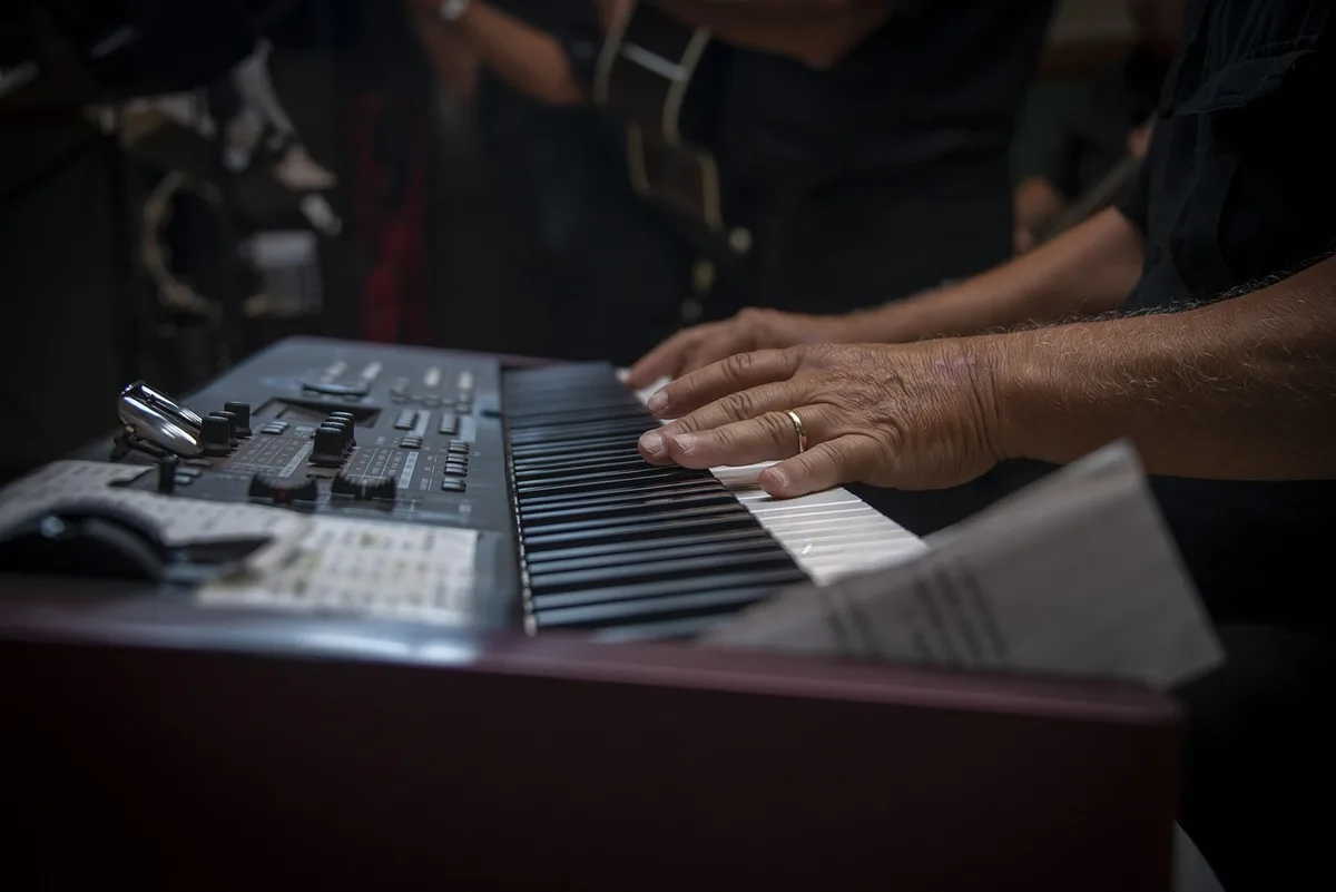 Mains d'une personne âgée jouant d'un instrument, illustration de coordination et écoute